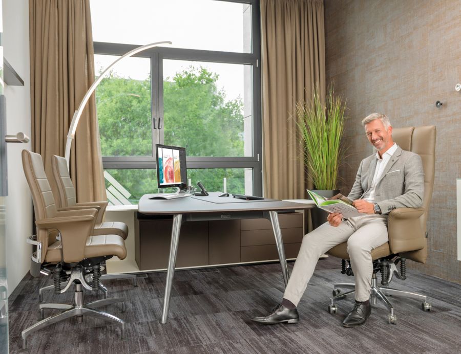 Mann sitzt im B&uuml;ro auf Chefsessel 780 iQ und liest. Gegen&uuml;ber des Schreibtisches stehen zwei Bioswing Besucherst&uuml;hle 660.