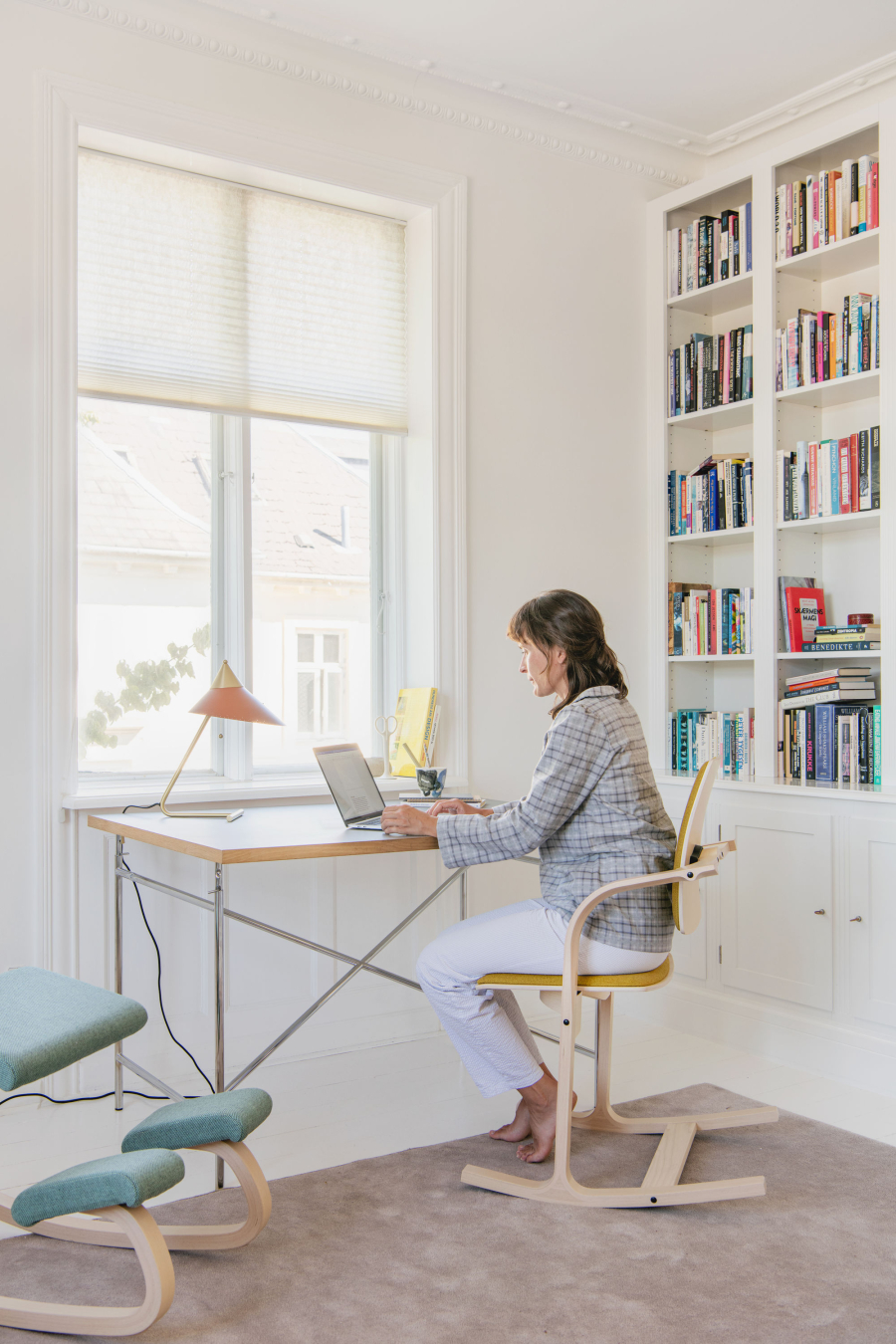 Junge Frau sitzt an modernem Schreibtisch mit dem Laptop auf einem Actulum Kufenstuhl