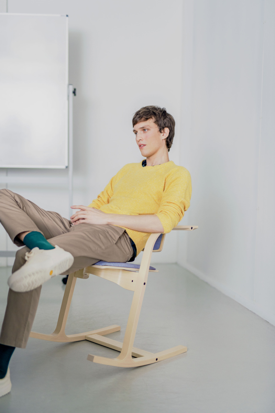 Junger Mann sitzt leger in angelehnter Position auf dem Kufenstuhl Varier / Stokke Actulum