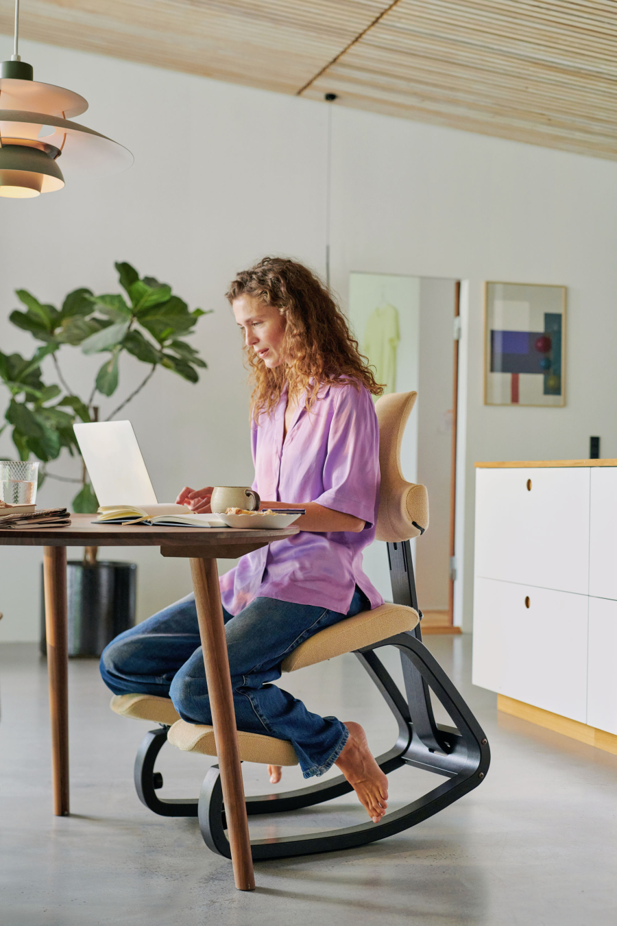 Frau auf dem Stokke Thatsit in Knieposition vorgeneigt am Holztisch